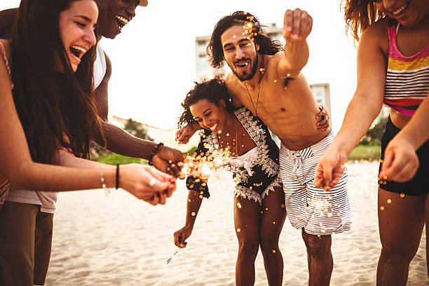 istock friends using a sparkler togetherness on the beach 503922108