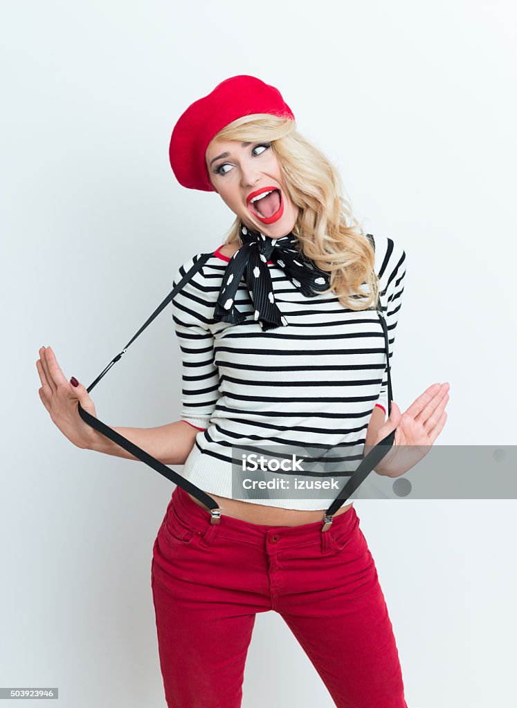 Cute blonde french woman wearing red beret Portrait of cute beautiful blonde woman in french outfit, wearing a red beret, striped blouse, suspenders and neckerchief. Adult Stock Photo