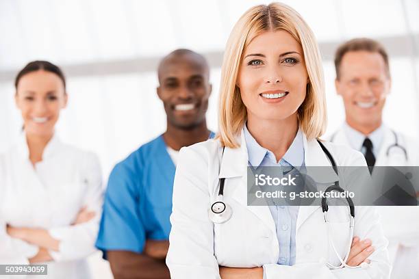 Confident In Her Team Stock Photo - Download Image Now - Female Doctor, Teamwork, Group Of People