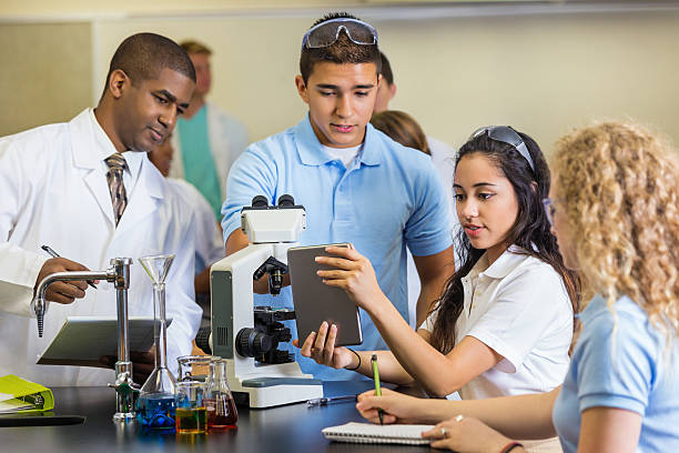 High school science teacher teaching students to use microscope High school science teacher teaching group of students to use microscope high school high school student science multi ethnic group stock pictures, royalty-free photos & images