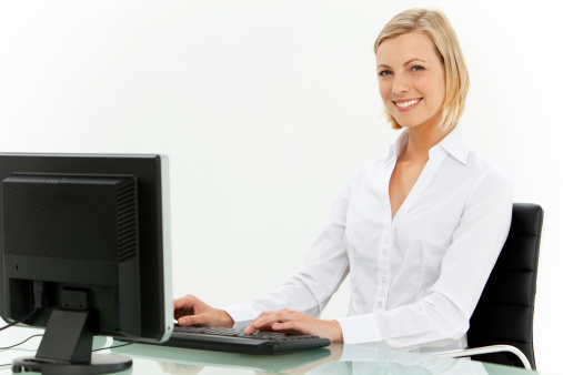 Portrait of a smiling young woman working on computer at workplace