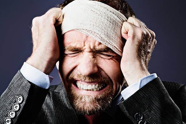 istock Agony: bandaged businessman grimaces, clutching his head 503947335
