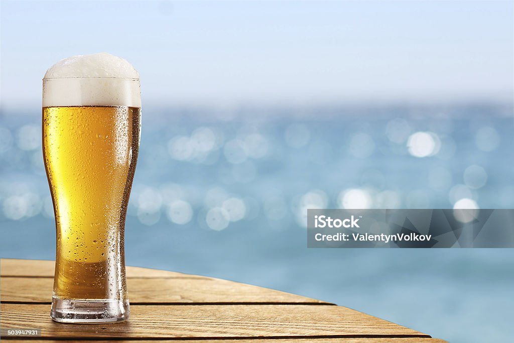 Birra in vetro su sfondo sfocato di mare. - Foto stock royalty-free di Birra