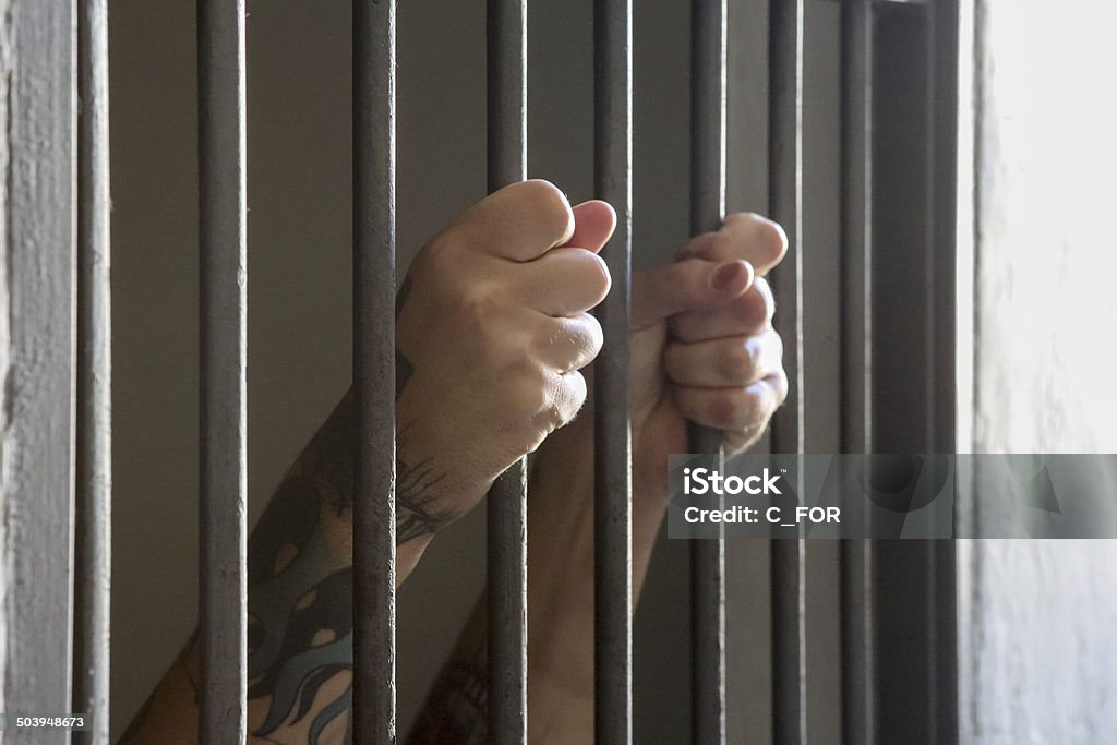 Prisoner hands - Incarceration Man behind prison bars. Behind Stock Photo