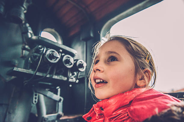 Girl in Pink Admiring Old Steam Locomotive, Europe Girl with long brown hair in pink winter jacket admiring an old steam locomotive at the Nova Gorica train station, Slovenia, Europe.  Side view, close-up.  Nikon D800, full frame, XXXL. nova gorica stock pictures, royalty-free photos & images