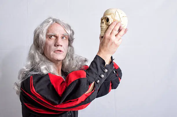Mature man dressed as Hamlet holding a skull