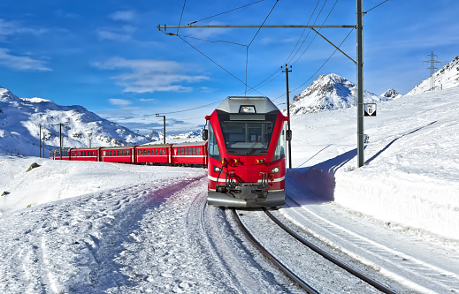 A red swiss train running through the snow, Switzerland