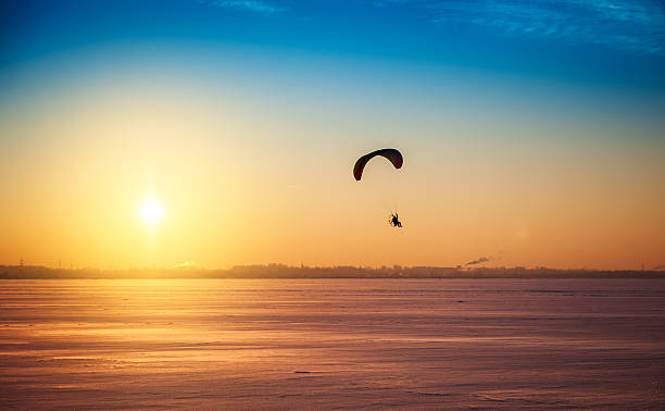 Beautiful winter sunset landscape with flying paraglider stock photo