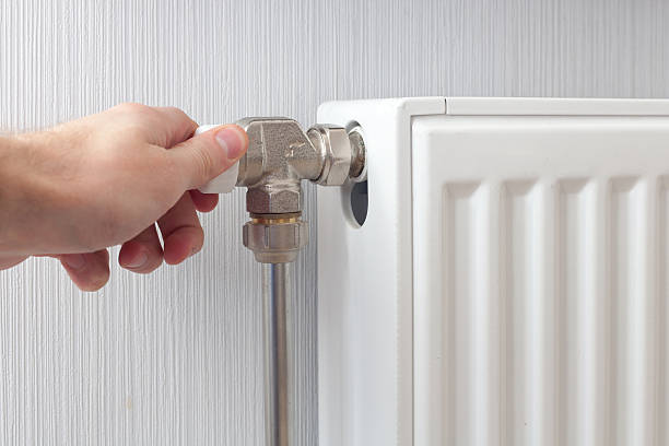 istock Radiator adjustment closeup. Man's hand adjusting radiator temperature. 503952134