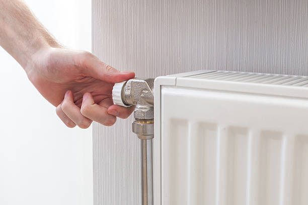 istock Radiator adjustment closeup. Man's hand adjusting radiator temperature. 503952172