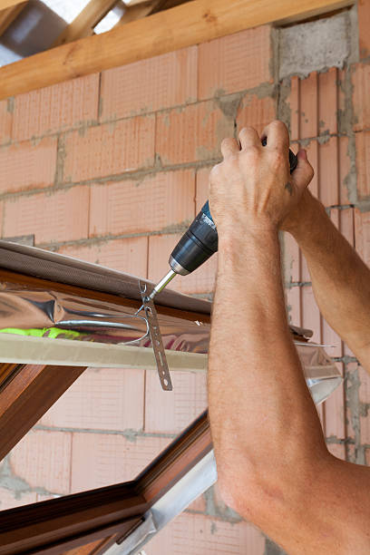 istock Plastic window installation. Worker attaches anchor plate with screwdriver 503953360