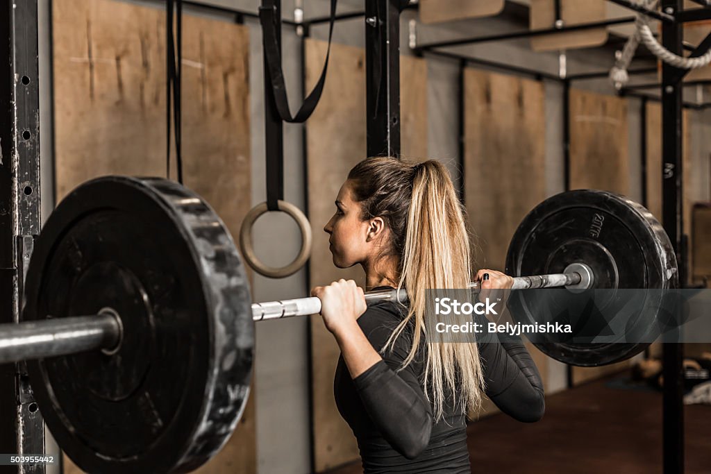 Giovane atleta femminile eseguire squat in palestra - Foto stock royalty-free di Cross training