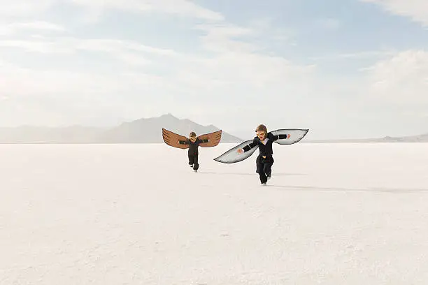 Photo of Young Business Boys Wearing Cardboard Wings Are Flying