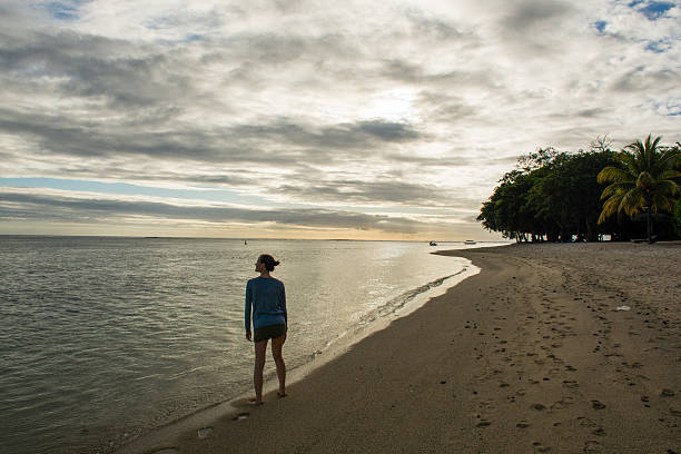 Girl looking at the calm water at sunset stock photo