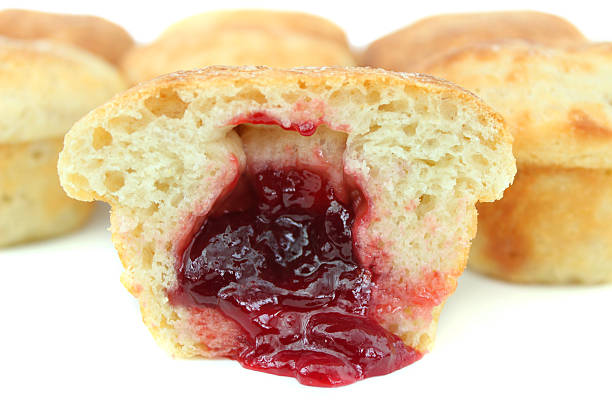 Photo showing a homemade jam doughnut / duffin muffin cake that has been sliced in half to show the strawberry jam hidden in the middle of the cupcake.