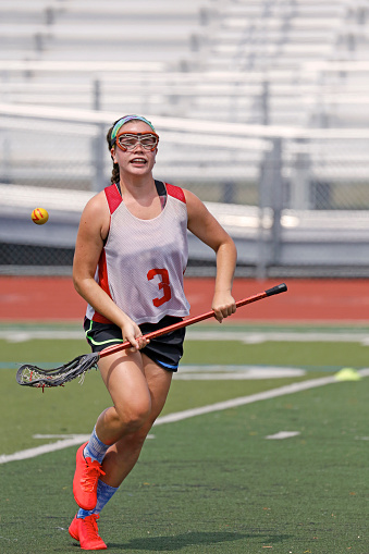 a girl tosses a lacrosse ball into the air
