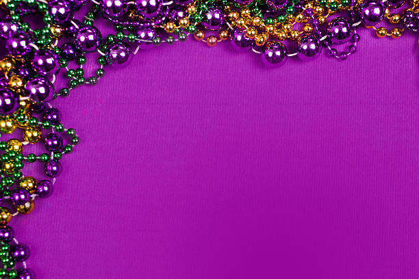 Mardi Gras background.  Colorful beads in purple, gold, and green Mardi Gras colors.  The necklaces are framed in corner of a purple background with copyspace at right.  The Mardi Gras festival is held every year in New Orleans Louisiana, USA.