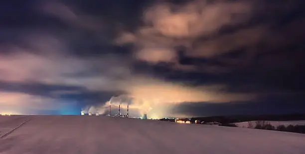 Nuclear power plant at night. Cloudy sky