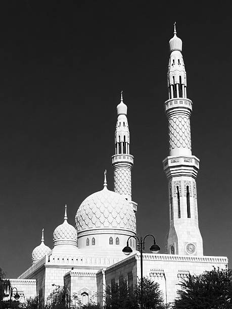 Mosque in Dubai, UAE A Mosque in Dubai with tall Minarets. Minaret also known as Goldaste or Minar. "lighthouse", is a distinctive architectural feature of mosques, generally a tall spire with a conical or onion-shaped crown, usually either free-standing or taller than associated support structure. The basic form of a minaret includes a base, shaft, and gallery. Styles vary regionally and by period. Minarets provide a visual focal point and are used for the call to prayer (azān). Toned image of Mosque Minaret with silhouette of shrubs in the foreground. azan stock pictures, royalty-free photos & images