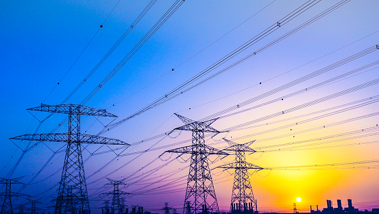 Electrical Pylons against vibrant twilight colors and a gorgeous sunset over Dubai Horizon.