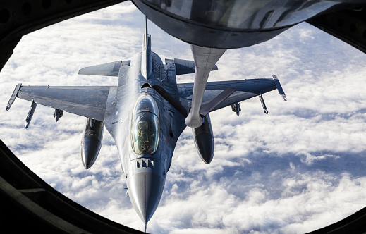 Mid-air refueling of a Fighter jet from the boom pod of a KC-135 Stratotanker. 