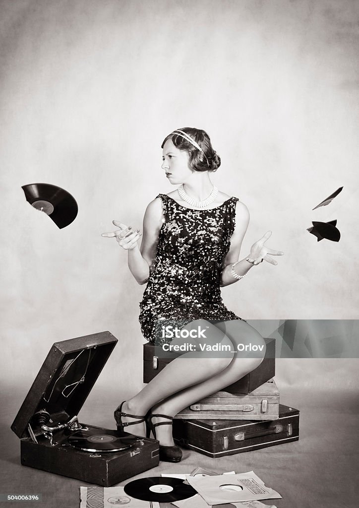 Upset girl scatters shards of broken gramophone records The picture was taken in a home studio photographer. Record - Analog Audio Stock Photo