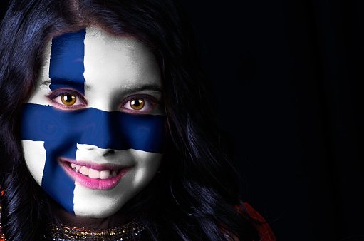 Close up portrait shot of a girl having Finnish flag painted on her face.