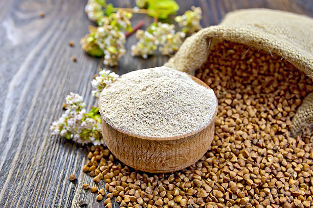 Flour buckwheat in bowl with cereals and flower on board Buckwheat flour in a wooden bowl, buckwheat in the bag, buckwheat flower on the background of wooden boards buckwheat photos stock pictures, royalty-free photos & images