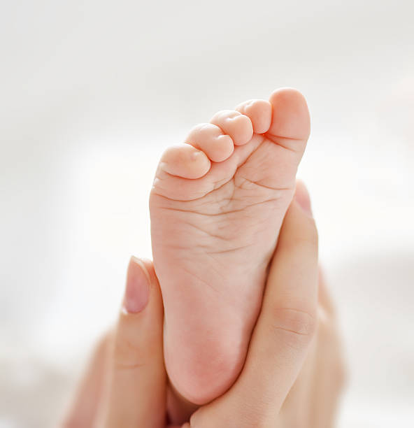 foot of a small baby the foot of a small baby in the hand of an adult human foot photos stock pictures, royalty-free photos & images