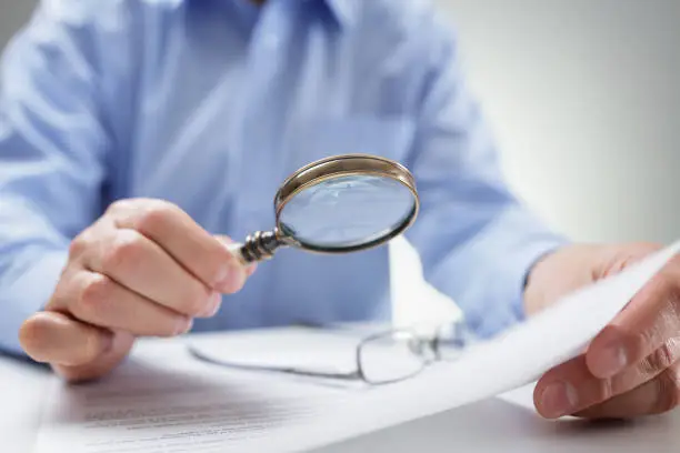 Photo of Businessman with magnifying glass reading documents