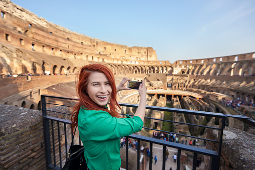 portrait of young woman at Colliseum smiling, capturing image of this great historical monument and enjoying her day.
