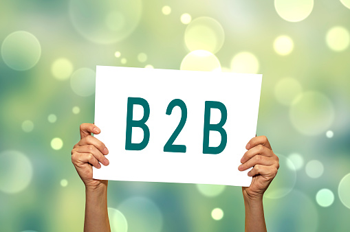 B2B (marketing) card in hand with abstract light background. Selective focus.