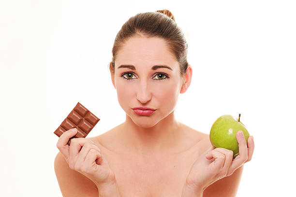istock Young woman choosing between apple and chocolate 504015390