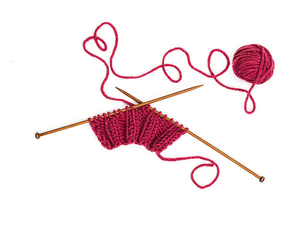 istock Knitting pattern on wooden needles of woolen threads red color 504017468