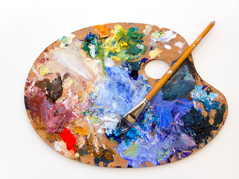 Colourful artists oil paint palette and brushes close up on plain background