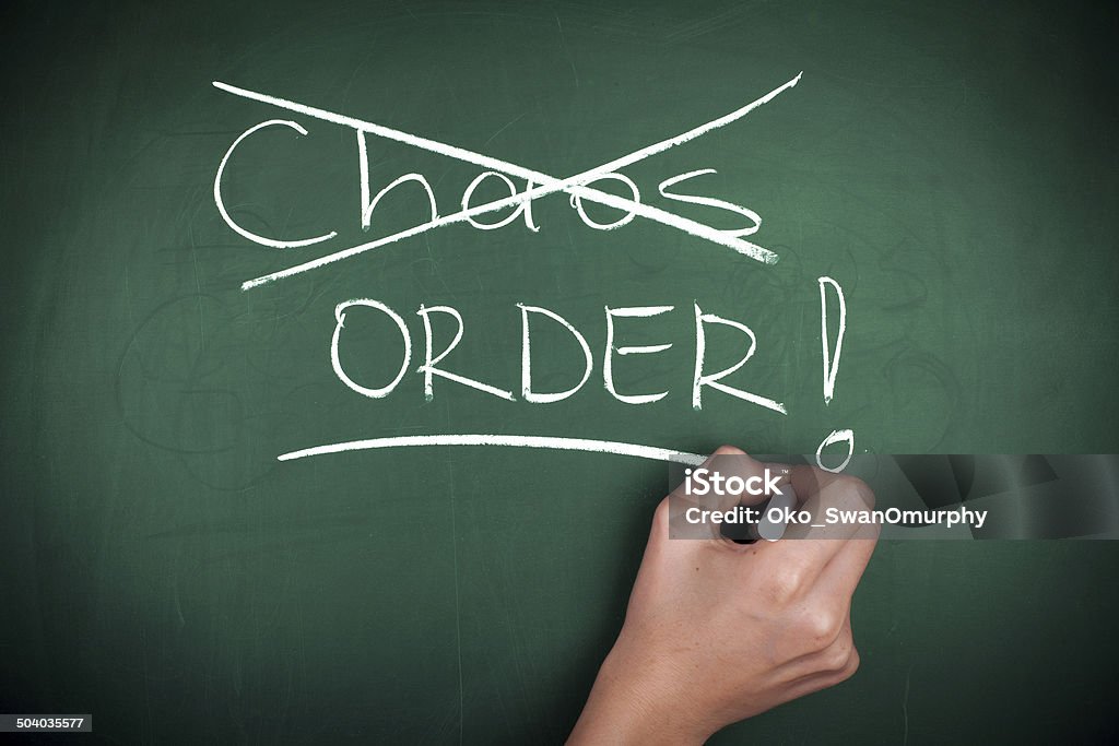 Chaos - Order Woman hand crossed out CHAOS and writing ORDER on green blackboard Order Stock Photo