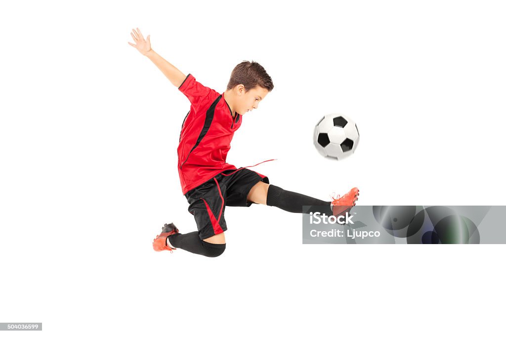 Junior football player kicking a ball Junior football player kicking a ball isolated on white background Child Stock Photo