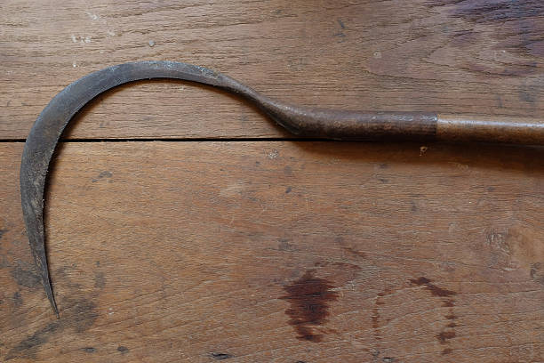 Sickle on wooden background.