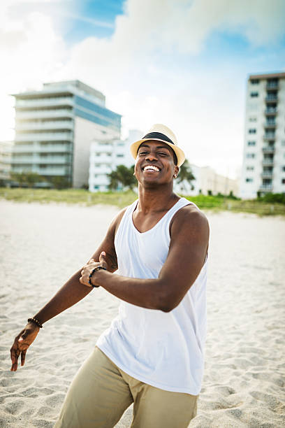 afrikanische mann tanzen am strand von miami - men latin american and hispanic ethnicity young men smiling stock-fotos und bilder