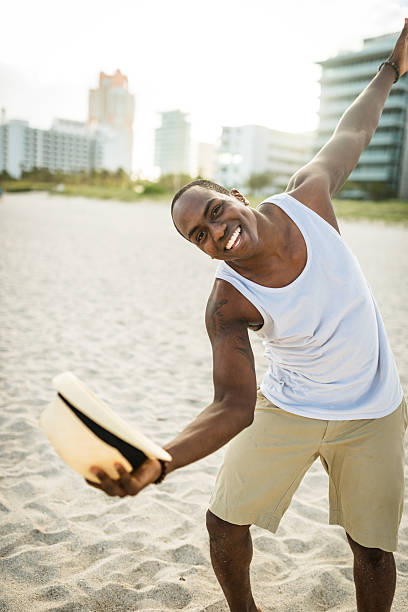 afrikanische mann tanzen am strand von miami - men latin american and hispanic ethnicity young men smiling stock-fotos und bilder