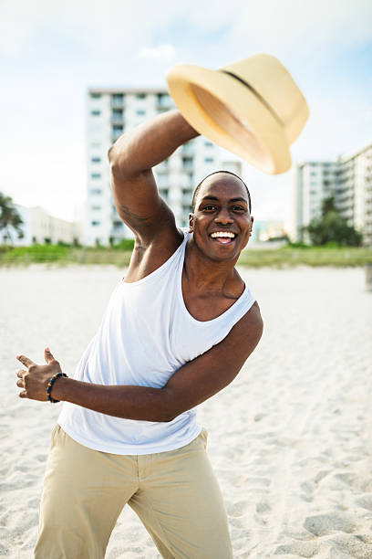 afrikanische mann tanzen am strand von miami - men latin american and hispanic ethnicity young men smiling stock-fotos und bilder