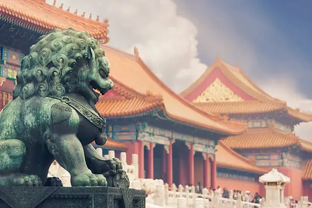 Old imperial lion sculpture in front of historical Forbidden City buildings.