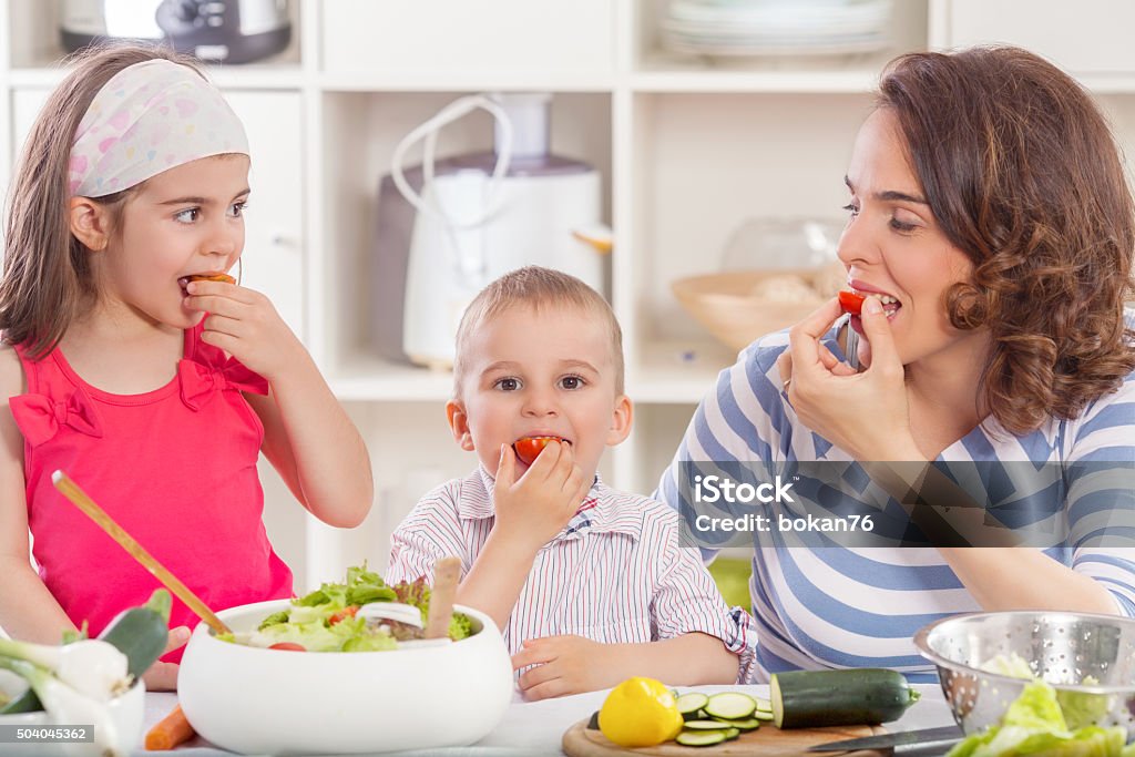 Eating Vegetables Happy young family preparing and eating vegetable salad Adult Stock Photo