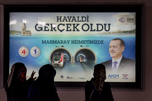 Istanbul, Turkey, - December 28, 2015: Veiled women looking at a poster promoting the opening of Marmaray Tunnel, an underground railway line passing under Bosphorus in Istanbul. This constructions has been used by Turkish President Erdogan to promote his action in the country