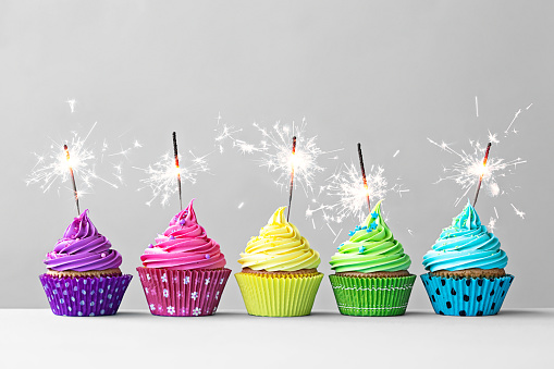 Row of colorful cupcakes with sparklers