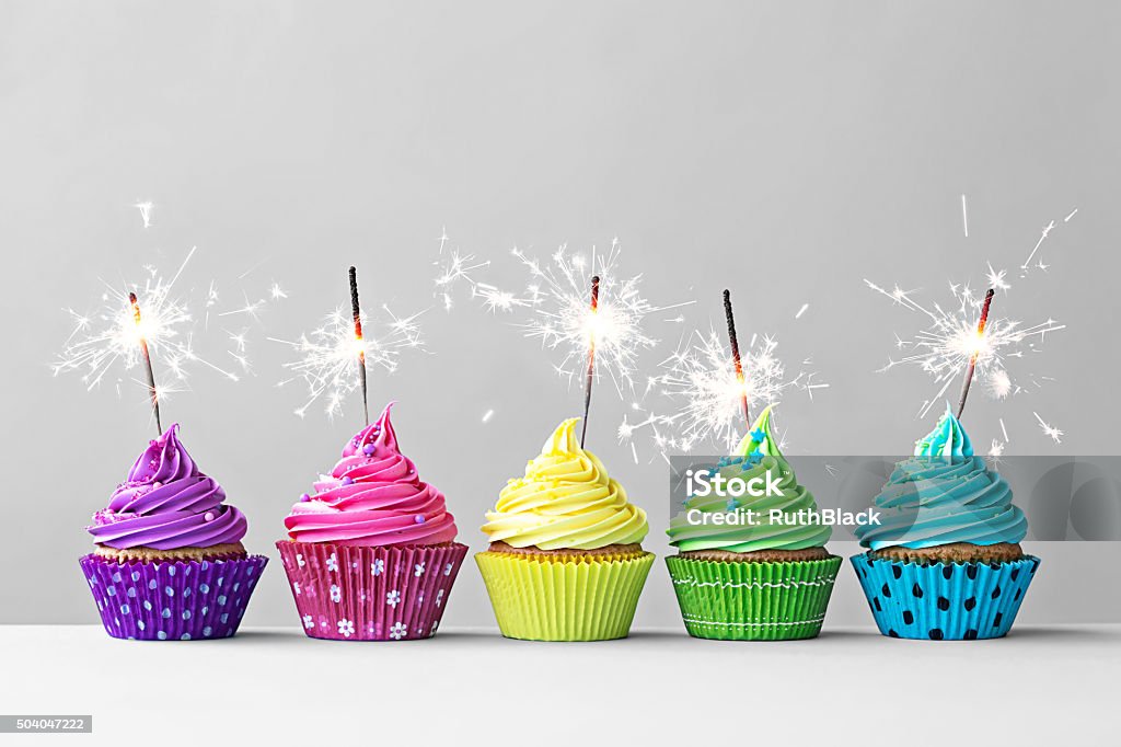 Colorful cupcakes with sparklers Row of colorful cupcakes with sparklers Birthday Stock Photo