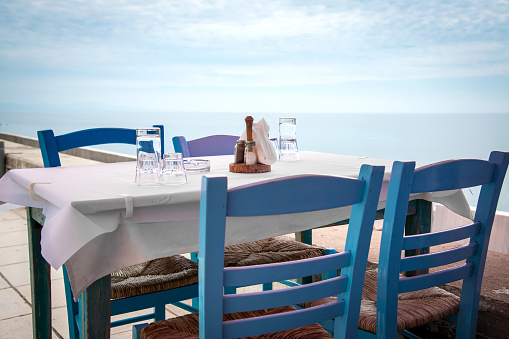 Greek tavern with blue wooden chairs by the aegean sea coast, Greece