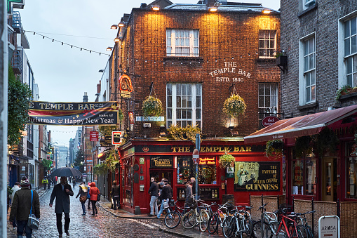 Dublin, Ireland - January 5, 2016: Pedestrians walking around street in Temple Bar during rainy evening. The area is the heart of tourism in the city.