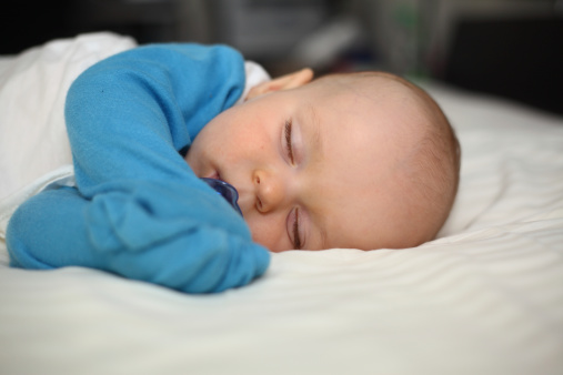 A close-up image of a cute Caucasian baby boy sleeping in his crib with a pacifier in his mouth. See more in my portfolio