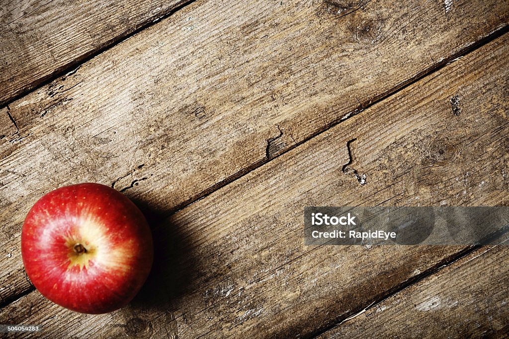 An apple a day. Single fruit on weathered wood A single, shiny red apple on weathered wood. Will this keep the doctor away? plenty of copy space on the wood. Apple - Fruit Stock Photo